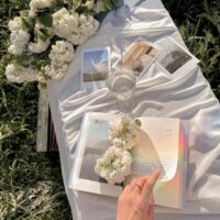 crop woman reading book on grass